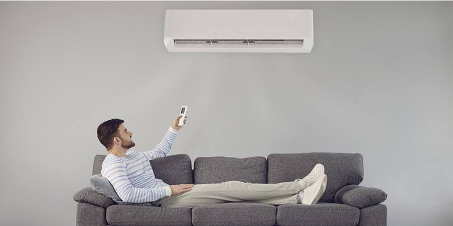 Man lying on the couch turning on a ductless unit
